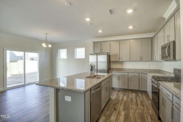 kitchen featuring crown molding, a center island with sink, pendant lighting, stainless steel appliances, and light stone countertops