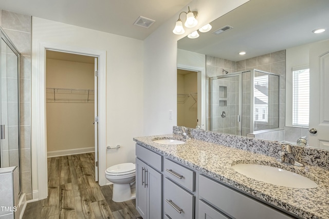 bathroom with vanity, wood-type flooring, toilet, and a shower with shower door