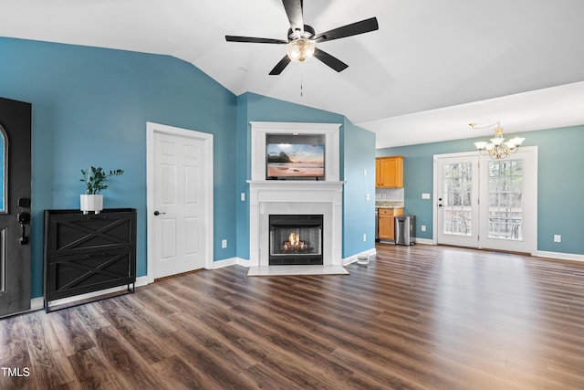 unfurnished living room with dark wood-type flooring, vaulted ceiling, a warm lit fireplace, baseboards, and ceiling fan with notable chandelier