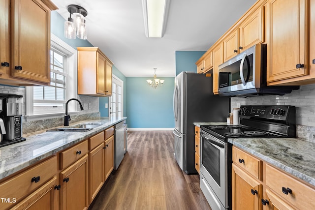 kitchen with decorative light fixtures, appliances with stainless steel finishes, dark wood-type flooring, a sink, and baseboards