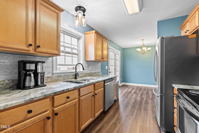 kitchen with dark wood-style floors, light stone counters, decorative light fixtures, stainless steel appliances, and a sink