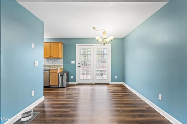 unfurnished dining area with dark wood-style floors, a notable chandelier, and baseboards