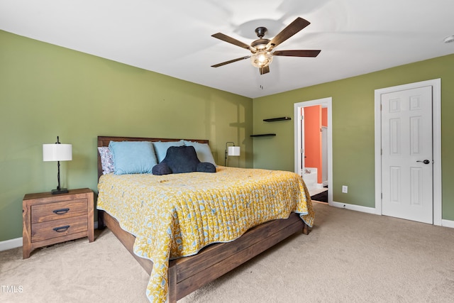 bedroom featuring ceiling fan, baseboards, ensuite bathroom, and light colored carpet