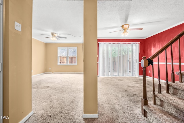 unfurnished living room with a ceiling fan, carpet floors, stairway, crown molding, and a textured ceiling