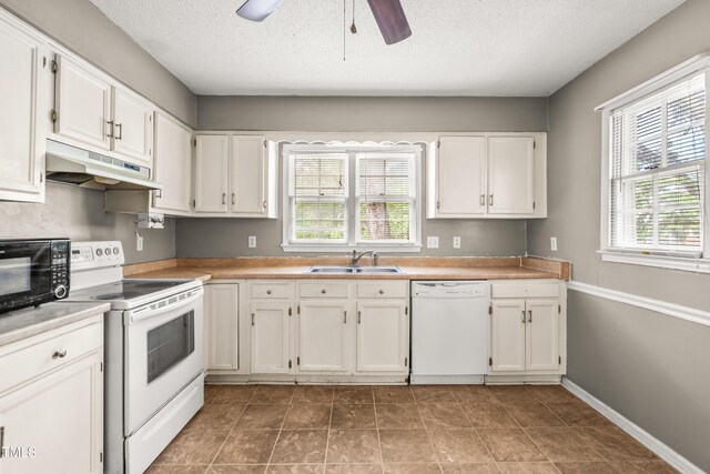 kitchen featuring white appliances, under cabinet range hood, a sink, white cabinets, and a textured ceiling