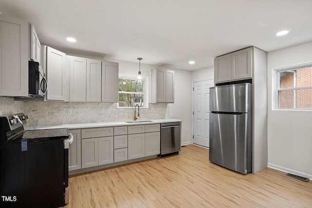 kitchen with gray cabinetry, sink, hanging light fixtures, and appliances with stainless steel finishes