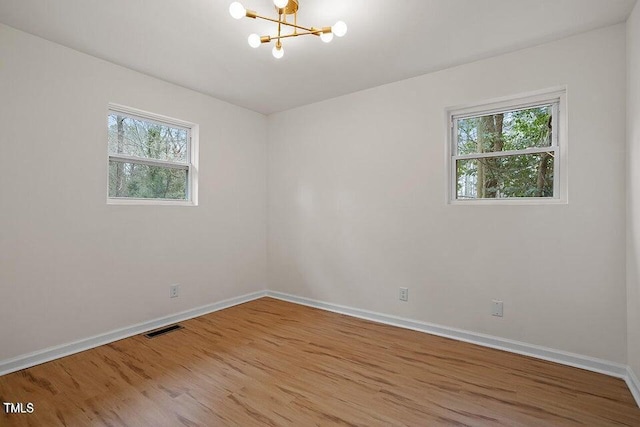 spare room with a chandelier and hardwood / wood-style floors