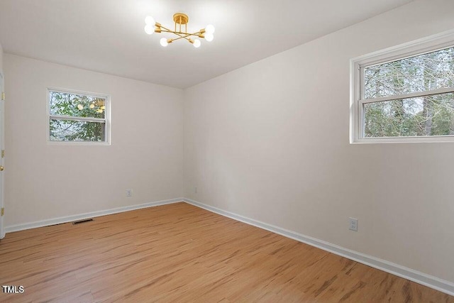 empty room with a chandelier and light hardwood / wood-style floors