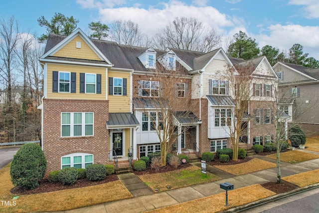 townhome / multi-family property with a standing seam roof and brick siding