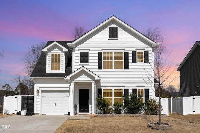 traditional-style home with a gate, fence, driveway, and a shingled roof