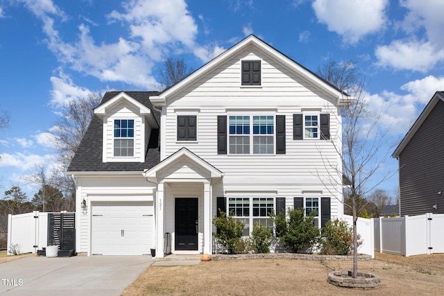 traditional-style home with a gate, roof with shingles, concrete driveway, and fence