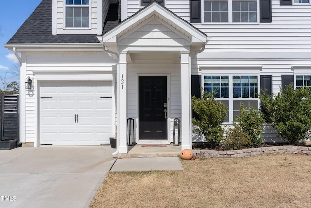 property entrance with concrete driveway and a shingled roof