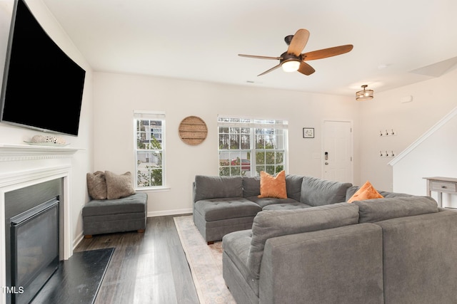 living room with a fireplace, baseboards, dark wood-type flooring, and a ceiling fan