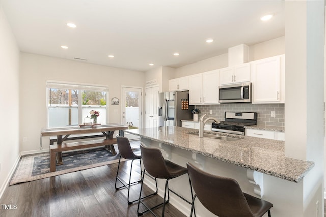 kitchen with a sink, tasteful backsplash, white cabinetry, and stainless steel appliances