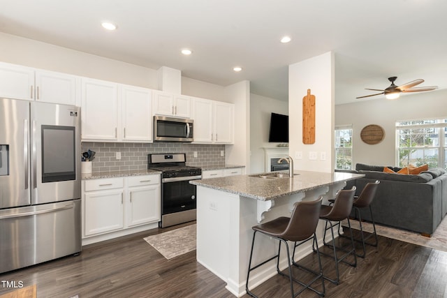 kitchen featuring open floor plan, white cabinets, stainless steel appliances, and a sink