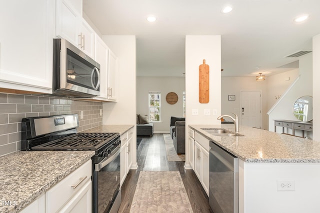 kitchen with visible vents, a sink, stainless steel appliances, white cabinetry, and backsplash