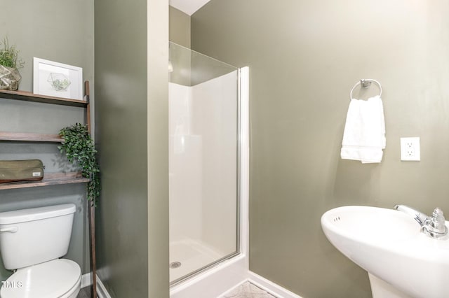 bathroom with a sink, baseboards, toilet, and a shower stall