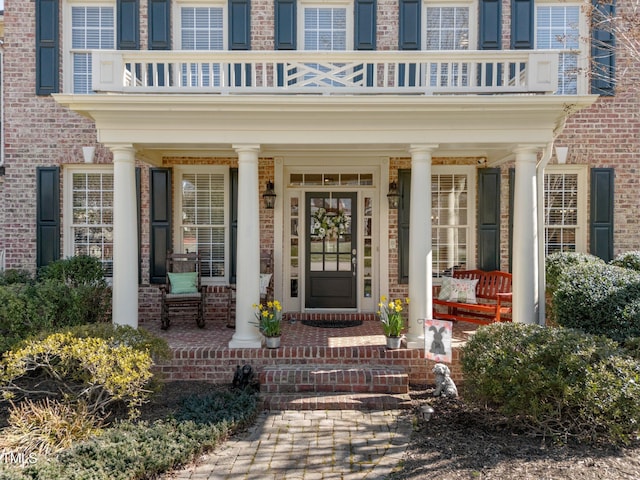 doorway to property with a porch and brick siding