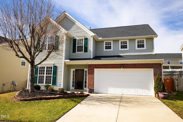 traditional home featuring brick siding, fence, a garage, driveway, and a front lawn