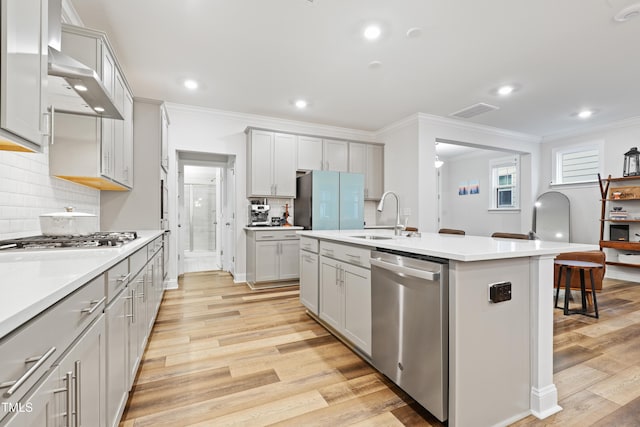 kitchen featuring appliances with stainless steel finishes, sink, a center island with sink, and light wood-type flooring