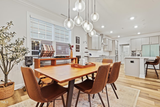 dining area with sink, crown molding, and light hardwood / wood-style flooring