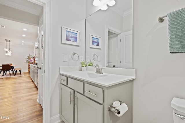 bathroom featuring vanity, crown molding, wood-type flooring, and toilet