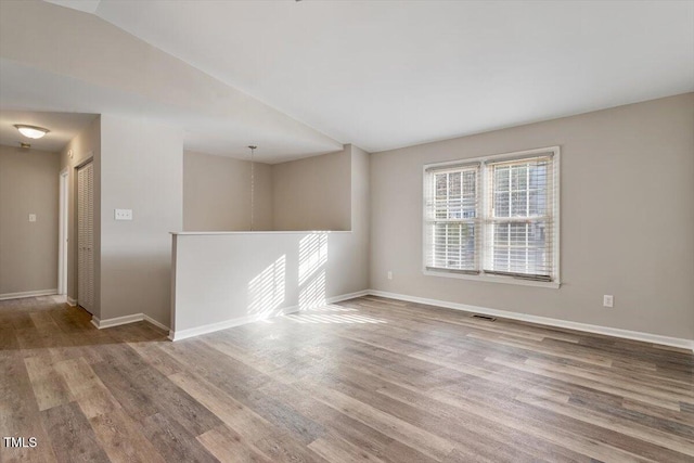 spare room with wood-type flooring and vaulted ceiling