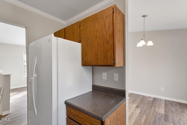 kitchen featuring crown molding, white fridge with ice dispenser, hanging light fixtures, light wood-type flooring, and a notable chandelier