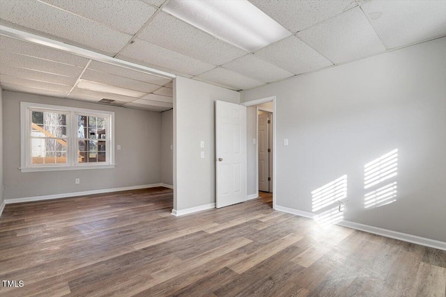 unfurnished room with a drop ceiling and hardwood / wood-style floors