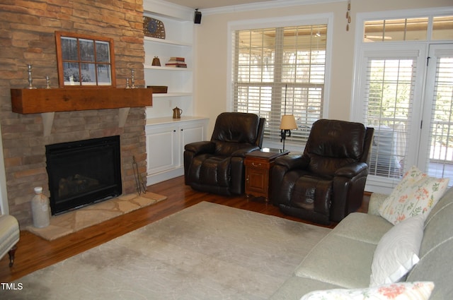 living room featuring built in features, a fireplace, ornamental molding, and dark wood-type flooring