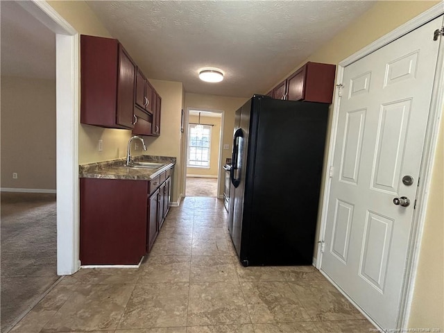 kitchen featuring black fridge with ice dispenser, sink, and a textured ceiling