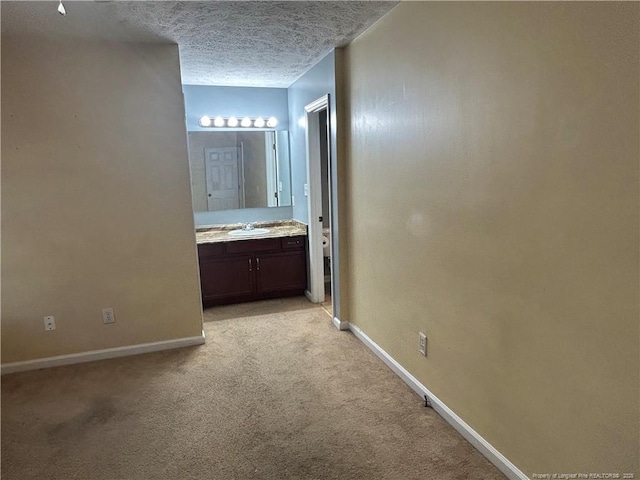 hall featuring sink, light colored carpet, and a textured ceiling