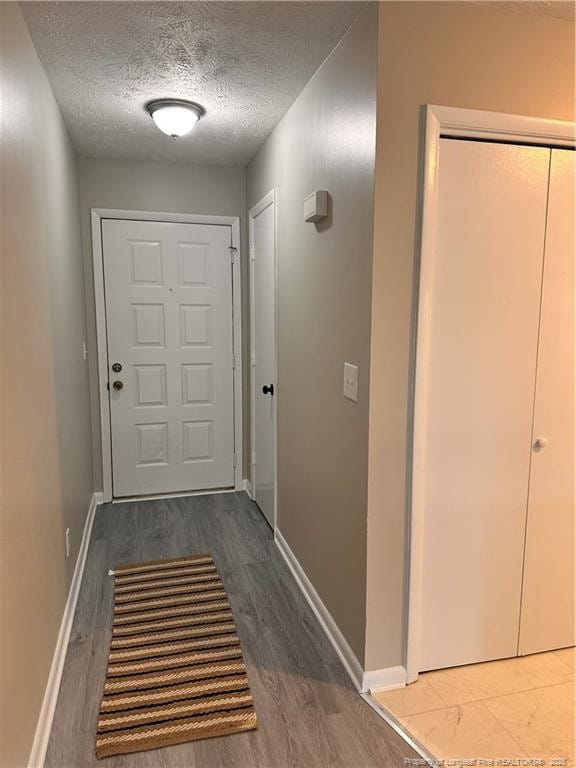 corridor featuring wood-type flooring and a textured ceiling