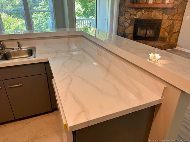 kitchen featuring light stone counters, a fireplace, and sink