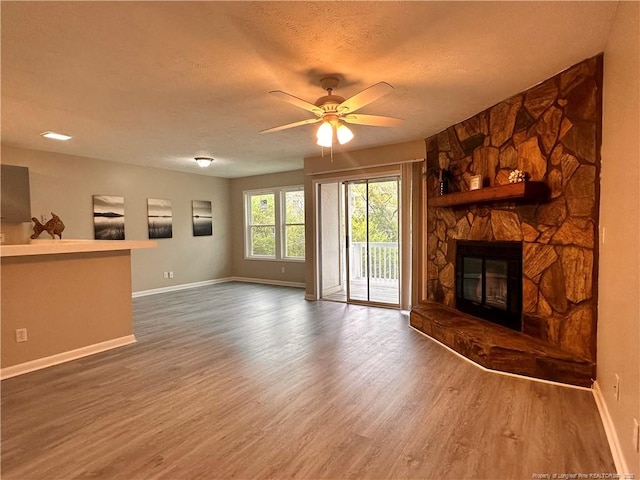 unfurnished living room with ceiling fan, hardwood / wood-style flooring, a fireplace, and a textured ceiling