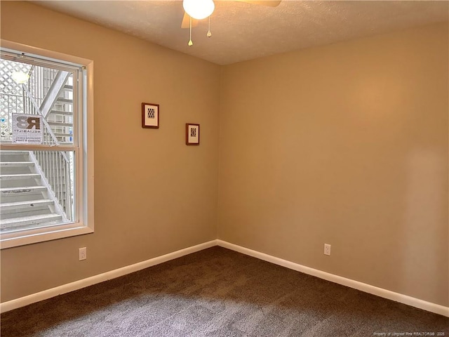 carpeted empty room featuring ceiling fan and a textured ceiling