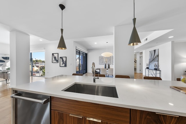 kitchen featuring stainless steel dishwasher, sink, and hanging light fixtures