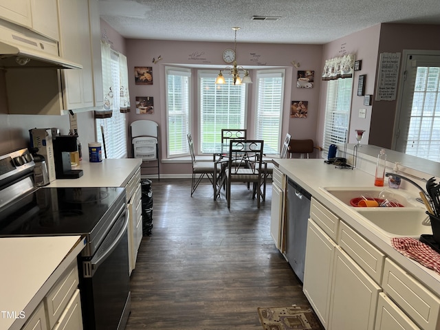 kitchen featuring dark wood-type flooring, sink, hanging light fixtures, a textured ceiling, and stainless steel appliances