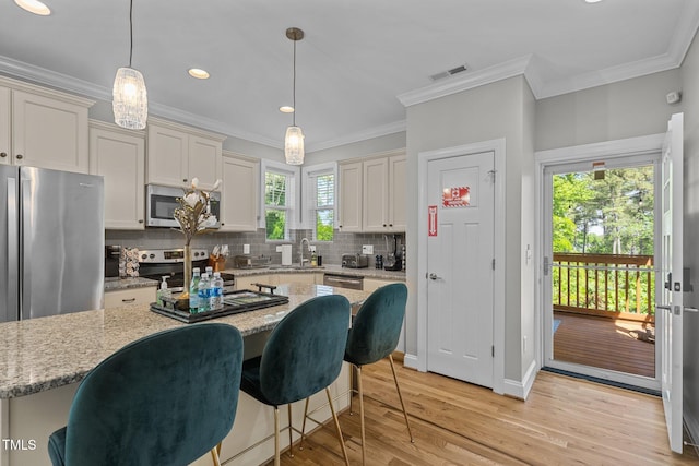 kitchen with tasteful backsplash, visible vents, light wood-type flooring, ornamental molding, and stainless steel appliances