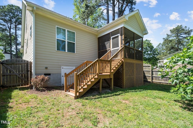 back of property with a lawn, a gate, fence, stairway, and a sunroom