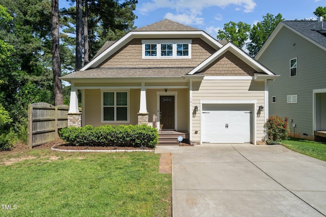 craftsman-style home with a front yard, fence, an attached garage, covered porch, and concrete driveway