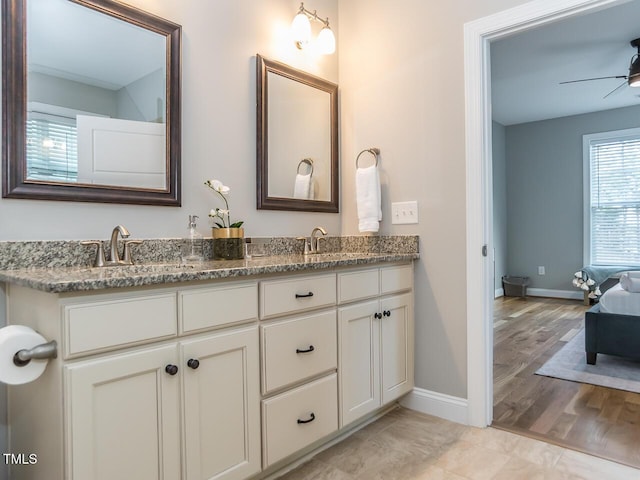 full bathroom with double vanity, baseboards, ceiling fan, and a sink