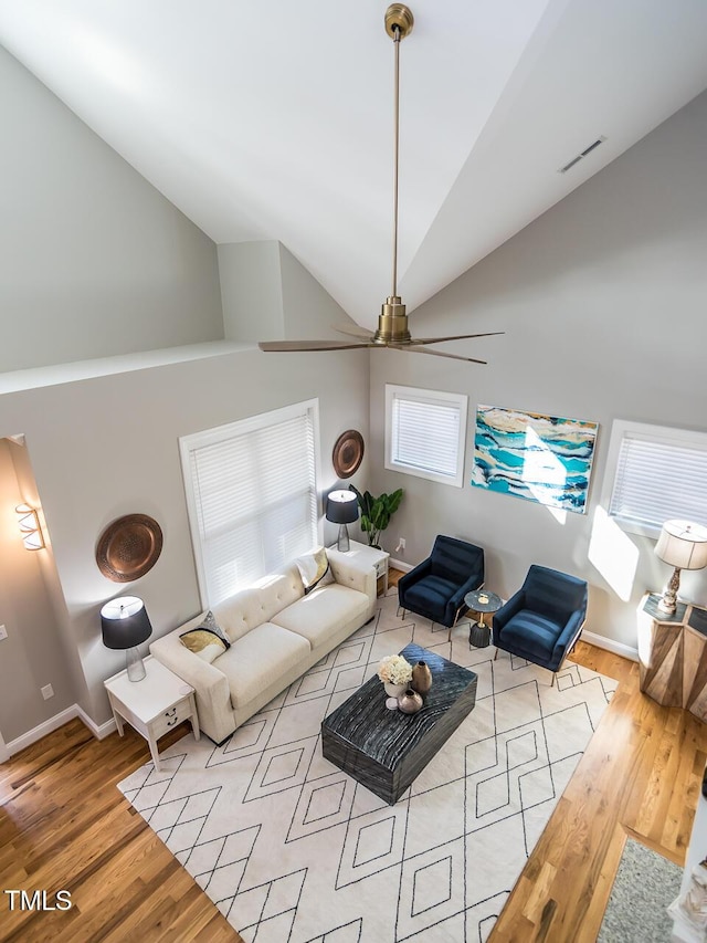 living area with visible vents, baseboards, high vaulted ceiling, and wood finished floors