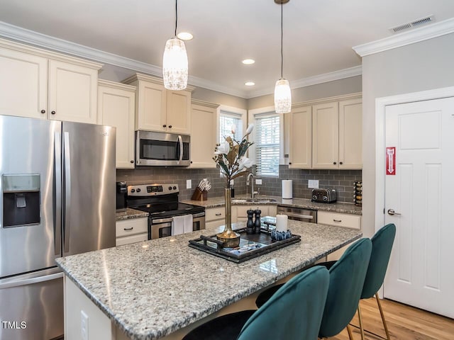 kitchen featuring visible vents, ornamental molding, appliances with stainless steel finishes, and a sink