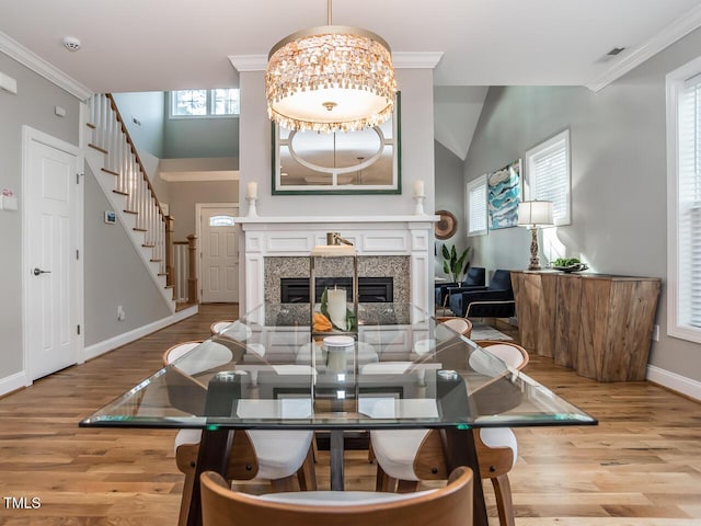 living room with a glass covered fireplace, wood finished floors, stairs, and ornamental molding