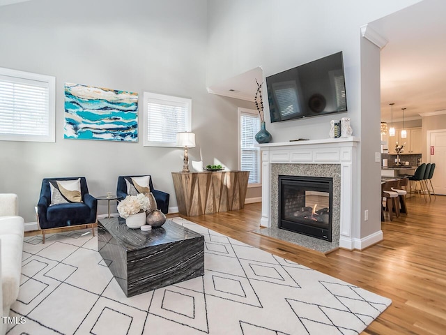 living room with baseboards, wood finished floors, a multi sided fireplace, and ornamental molding