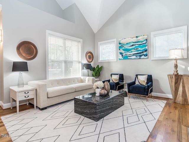 living room featuring high vaulted ceiling, baseboards, and wood finished floors