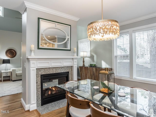 dining room with a multi sided fireplace, a chandelier, light wood-type flooring, and crown molding