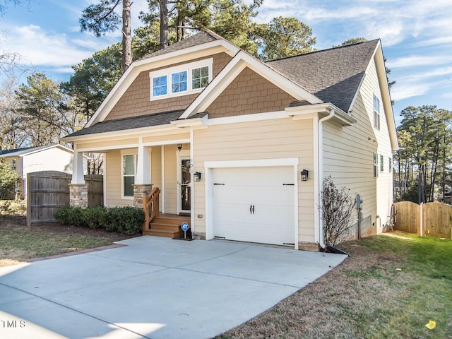 craftsman inspired home featuring fence, roof with shingles, an attached garage, covered porch, and concrete driveway