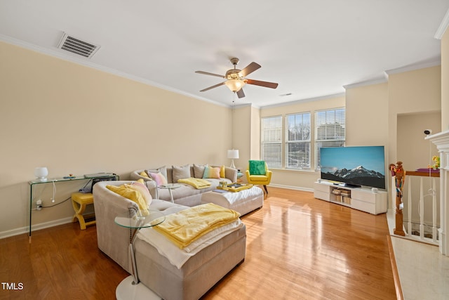 living room with baseboards, visible vents, a ceiling fan, ornamental molding, and light wood-type flooring